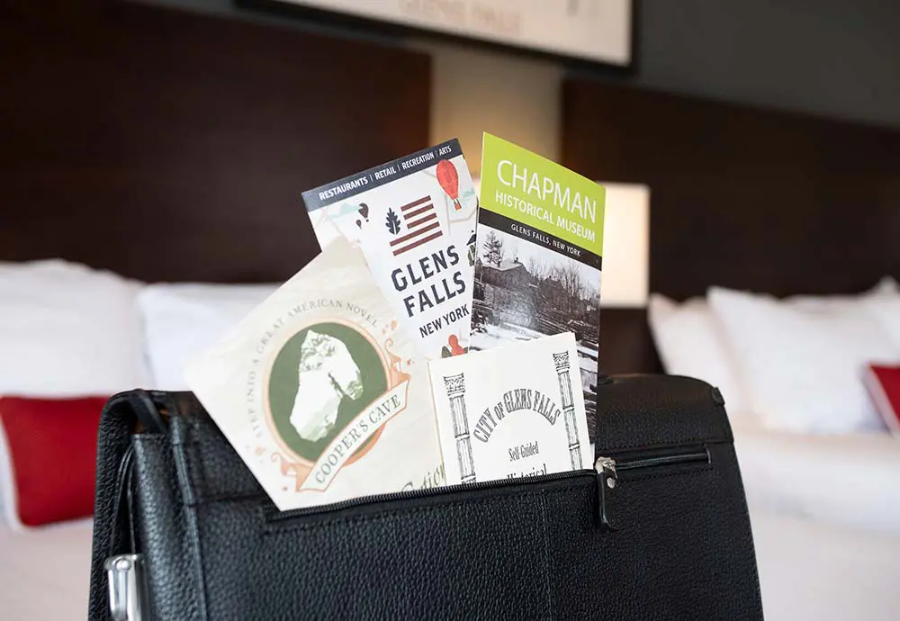Area brochures sticking out of leather folder on bed
